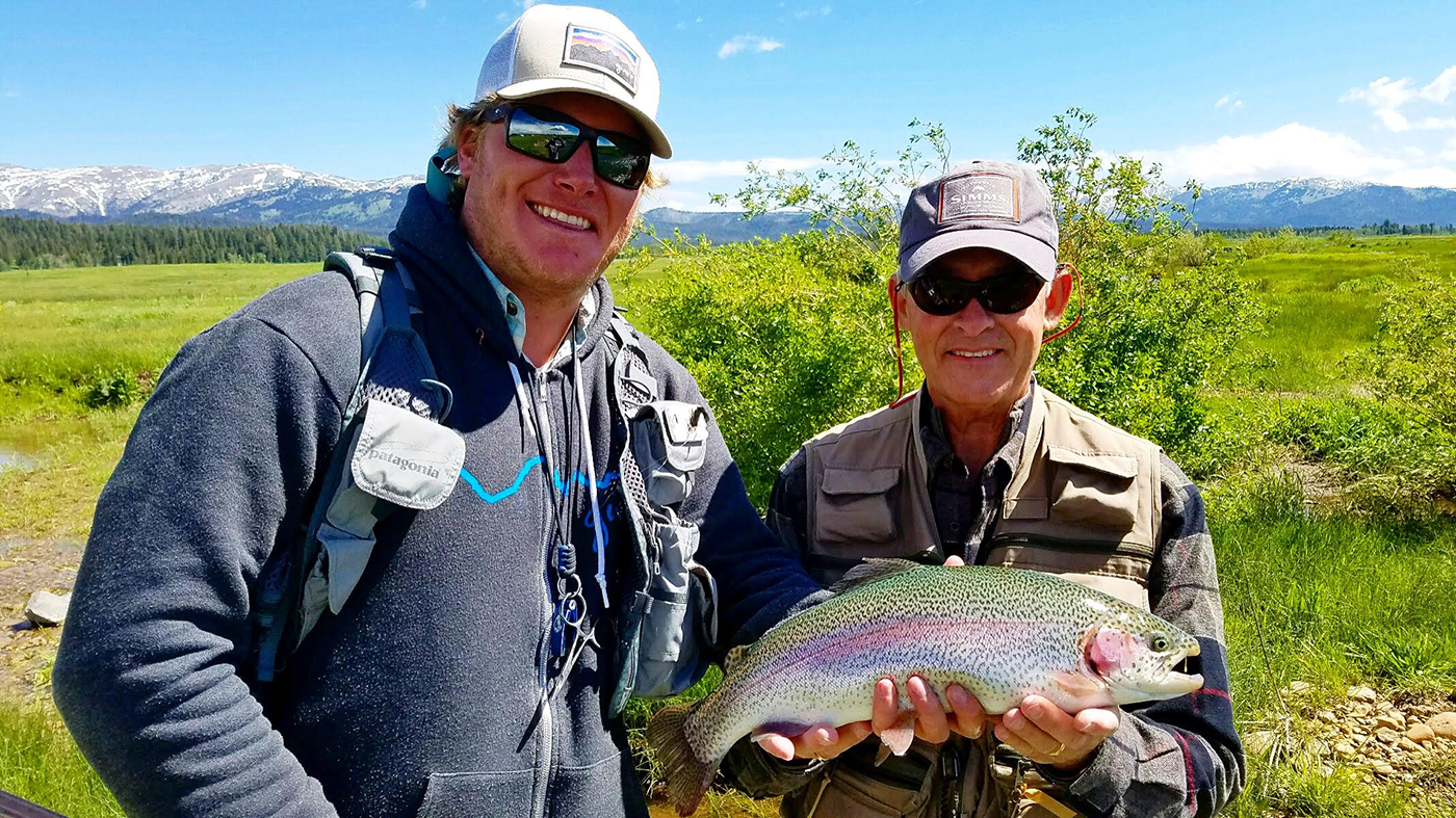 Jon Lewis and client hold up a large rainbow trout