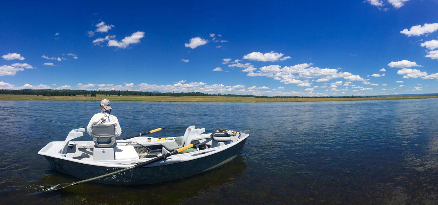 Fly fisherman watches for rises from a drift boat on the Henry's Fork